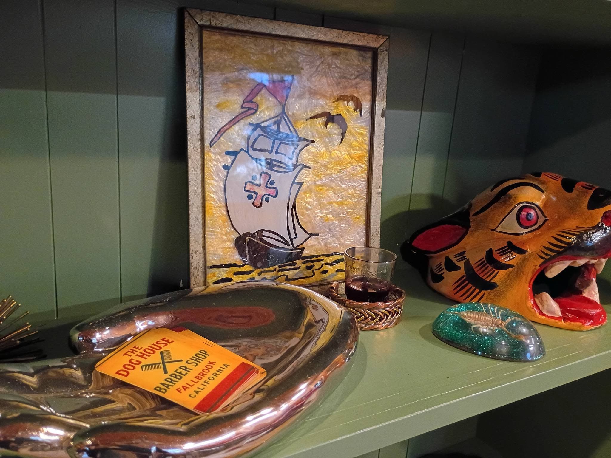 Decorative items on shelf with framed ship artwork